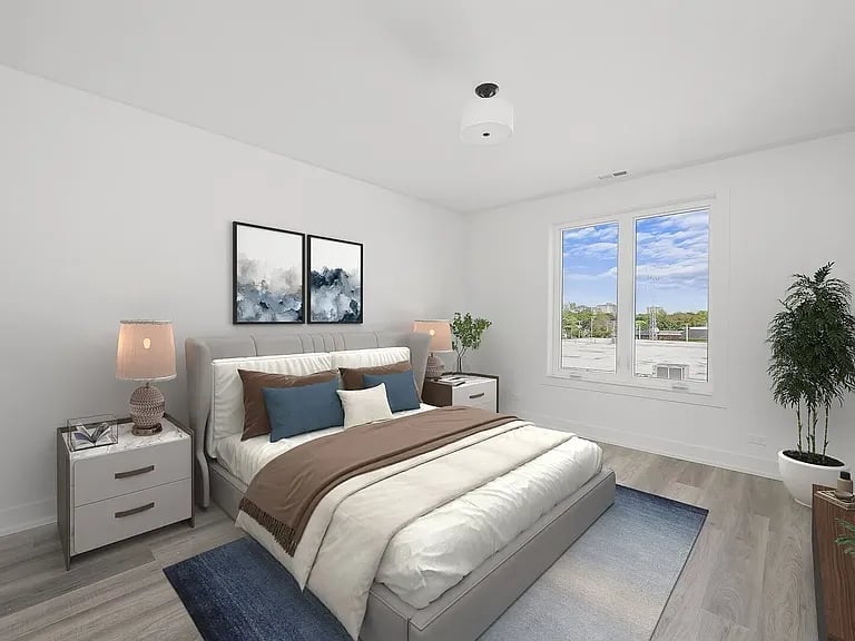 Modern bedroom with gray platform bed, white nightstands, large windows overlooking landscape, framed artwork, potted plant, and beige hardwood flooring